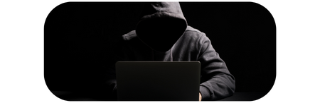 Hooded figure in front of a laptop