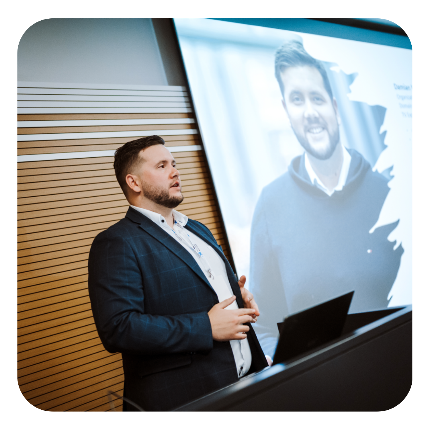 Speaker during a presentation — explaining slides at a large screen with a portrait